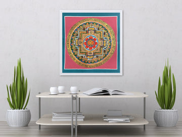 Hand-painted double vajra mandala in a white frame with a mat, above a table: a crossed vajra on a red lotus at the centre