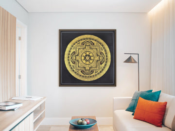Hand-painted Endless Knot mandala in gold on black, in a dark frame in a living room: the knot sits at the centre of the palace