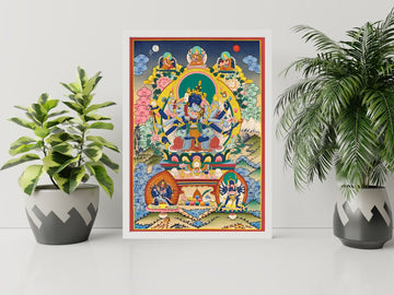 Hand-painted Guhyasamaja thangka in a white frame between two plants: the blue deity with his consort, three figures above and two smaller deities below