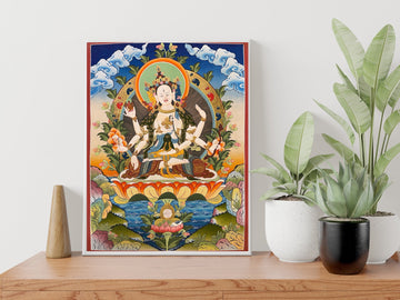 Hand-painted Namgyalma thangka in a white frame on a wooden sideboard: the white three-faced, eight-armed goddess on a lotus