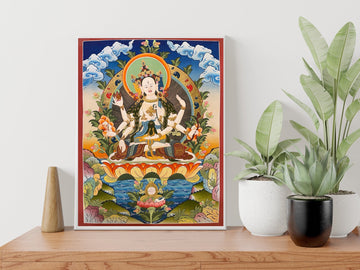 Hand-painted Namgyalma thangka in a white frame on a wooden sideboard: the white three-faced, eight-armed goddess on a lotus