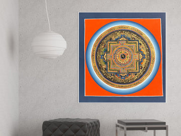 Hand-painted seed syllable mandala on an orange ground, framed on a grey wall: a single syllable at the centre of the palace