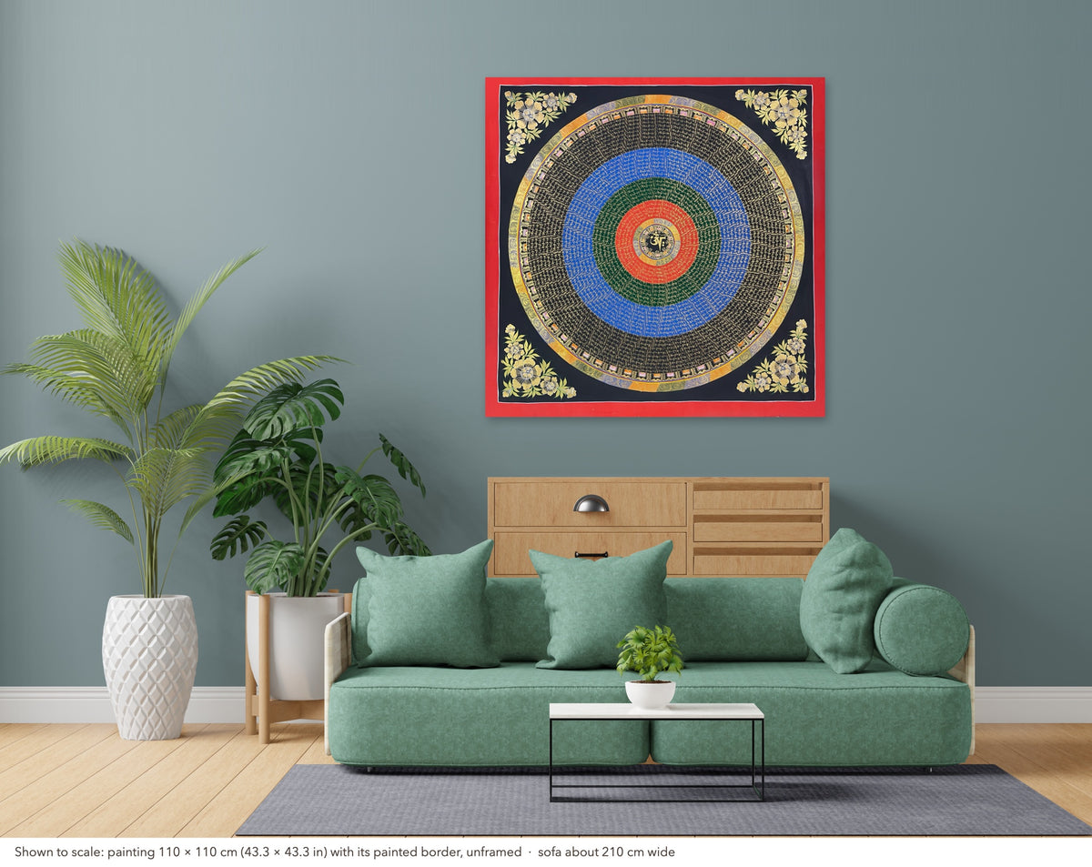 Mantra Mandala thangka shown to scale in a living room, unframed, above a sofa about 210 cm wide (110×110 cm)