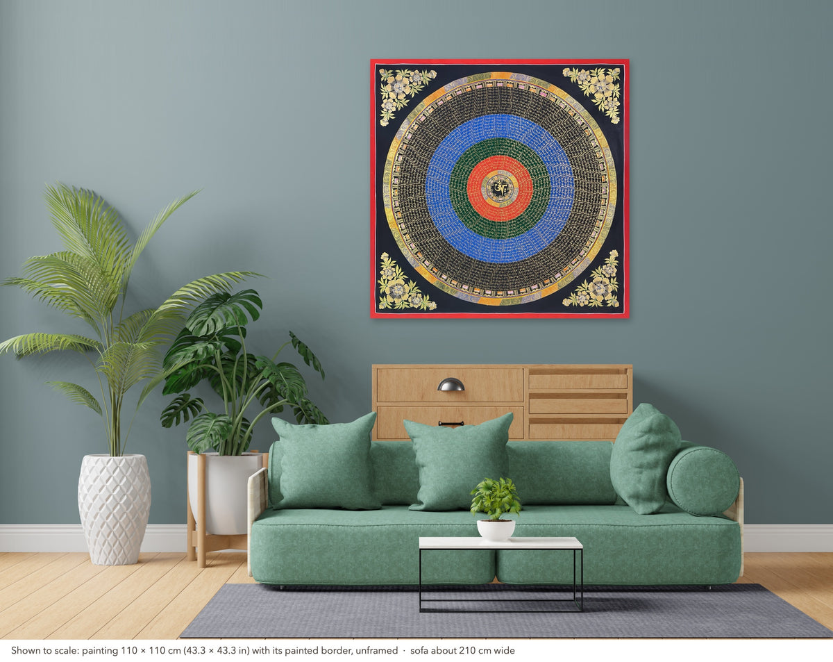 Mantra Mandala thangka shown to scale in a living room, unframed, above a sofa about 210 cm wide (110×110 cm)