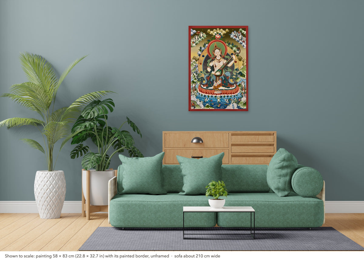 Saraswati thangka shown to scale in a living room, unframed, above a sofa about 210 cm wide (58×83 cm)