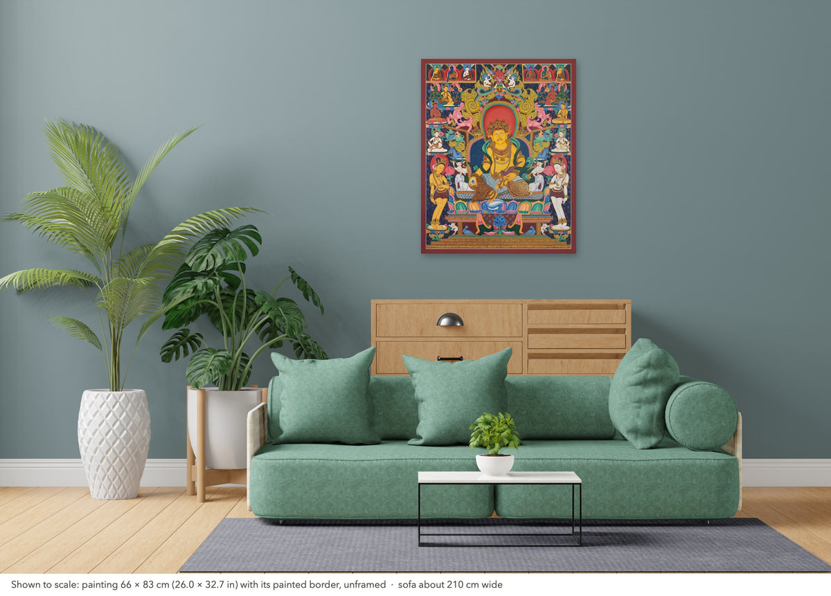 Yellow Jambhala thangka shown to scale in a living room, unframed, above a sofa about 210 cm wide (66×83 cm)