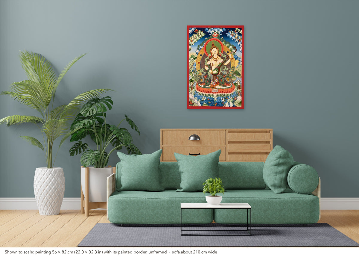 Saraswati thangka shown to scale in a living room, unframed, above a sofa about 210 cm wide (56×82 cm)