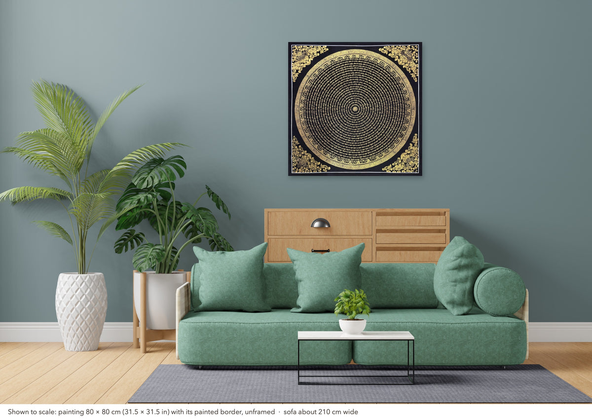 Mantra Mandala thangka shown to scale in a living room, unframed, above a sofa about 210 cm wide (80×80 cm)