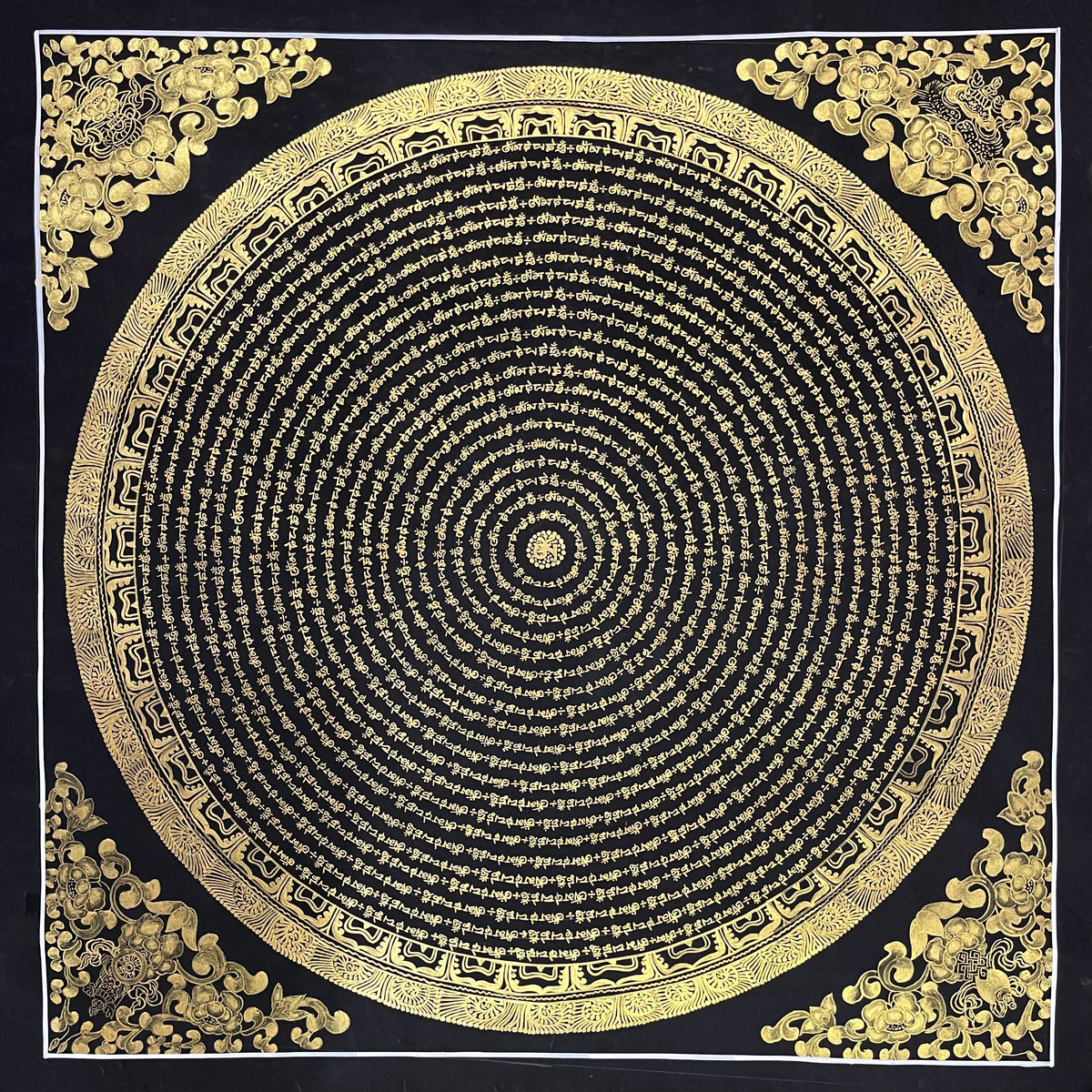 Mantra Mandala thangka, 80×80 cm: concentric rings of gold-coloured mantra script on black, with gold-coloured peonies in the corners