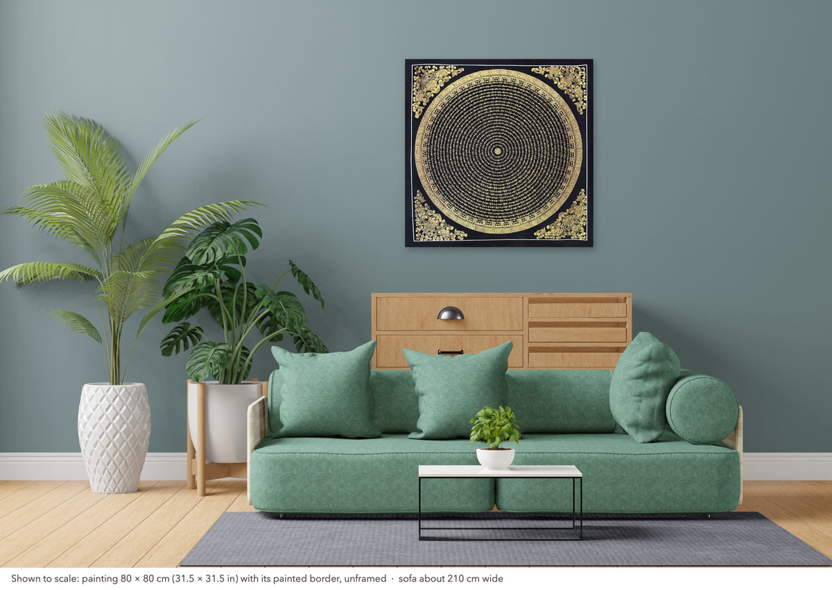 Mantra Mandala thangka shown to scale in a living room, unframed, above a sofa about 210 cm wide (80×80 cm)
