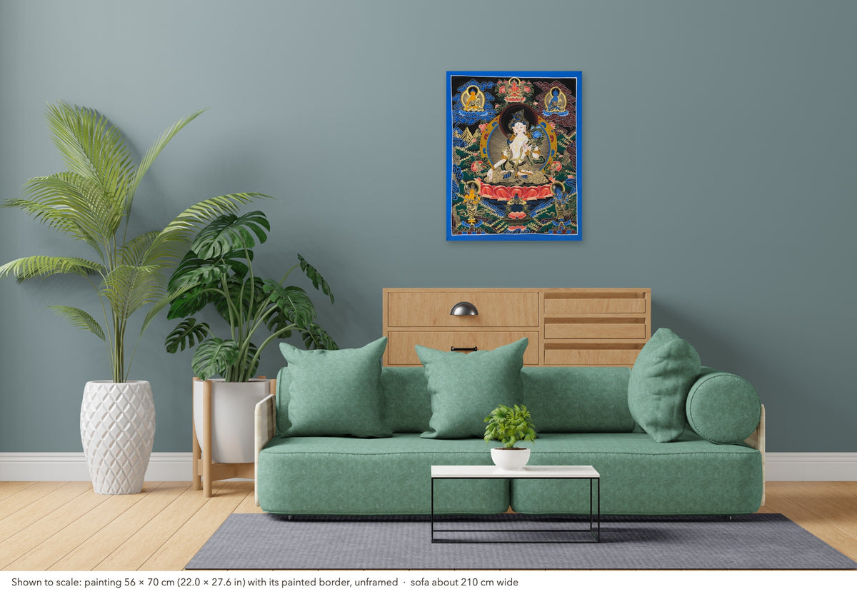 White Tara thangka shown to scale in a living room, unframed, above a sofa about 210 cm wide (56×70 cm)