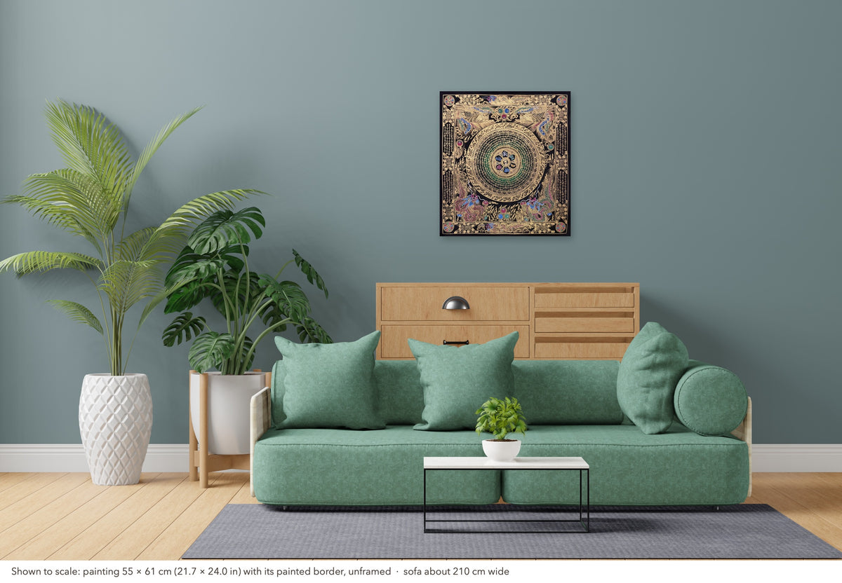 Mantra Mandala thangka shown to scale in a living room, unframed, above a sofa about 210 cm wide (55×61 cm)