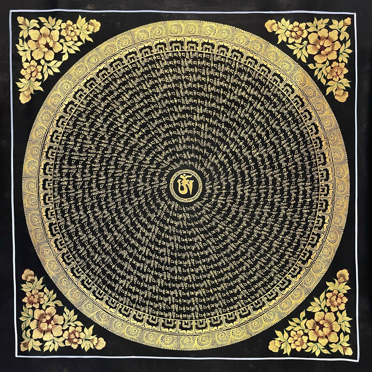 Mantra Mandala thangka, 77×77 cm: a spiral of gold-coloured mantra script on black around a central Om, with gold-coloured peonies in the corners